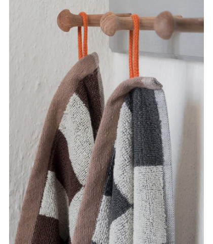 Håndklæde med skønne detaljer. Lysbrun kantbånd og orange strop og label. Mette Ditmers stilfulde håndklæde til dit badeværelse.
