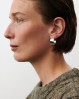 Pernille Corydon Large Reflection Hoops - Inspireret af nordisk lys og enkelhed, fremhæver deres brede, buede former den spejlblanke overflade, der leger med lyset. Perfekte som et moderne, selvsikkert statement både til hverdag og aften. Lavet af forgyldt genanvendt messing, tilbyder disse øreringe en udsøgt minimalistisk stil. En klassisk og tidløs tilføjelse til din smykkesamling.