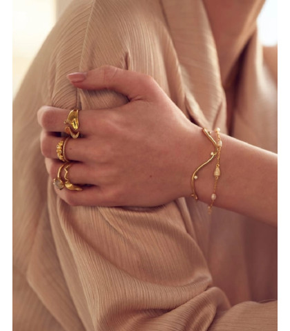 Denne armring i blankt 925 sterlingsølv omfavner håndleddet med sin bølgende form og fanger lyset med sine bløde kurver. Små, funklende zirkoner tilføjer et strejf af glans, mens det åbne design sikrer nem påtagning og en fleksibel pasform. 