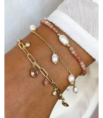 Dette feminine armbånd kombinerer rå elegance med fine detaljer, prydet med charms i forskellige størrelser og nuancer. De rosa zirkoniasten og varme sunstones giver et eksklusivt farvespil.