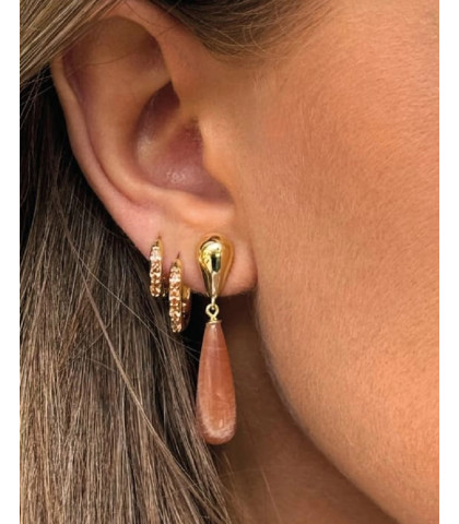 Disse elegante øreringe har en blankpoleret dråbeformet ørestik, hvorfra en rosa sunstone hænger og fanger lyset. Kombinationen af guld og rosaton skaber et sofistikeret udtryk, perfekt til både hverdag og fest.