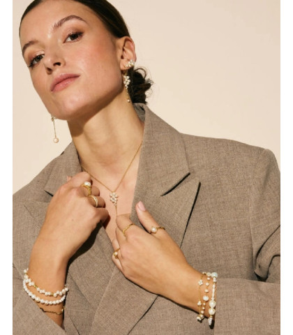 Dette raffinerede armbånd er kendetegnet ved små, fine perleklynger, der pynter en slank forgyldt sølvkæde. Dets diskrete detaljer og justerbare kæde sikrer en perfekt pasform og et luftigt, moderne look til både hverdag og fest. 